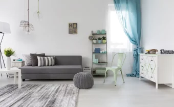 Svetlá obývačka so sivou pohovkou, zelenou stoličkou a modrými závesmi, ktorá kombinuje pohodlie s čistými farbami pre pokojnú atmosféru.