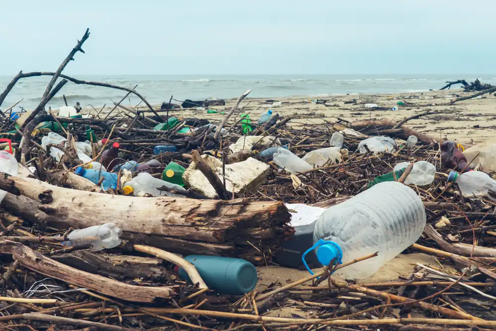 Kopa plastového odpadu na piesočnatej pláži po búrke, ilustrujúca priamy dopad ľudskej činnosti na znečistenie oceánov.