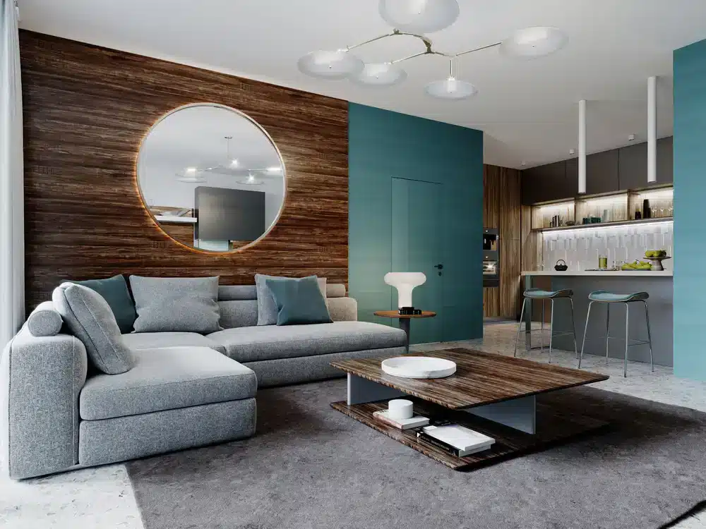 Elegantná obývacia izba s modrozelenými stenami a dreveným obkladom. Veľké kruhové zrkadlo nad pohovkou.