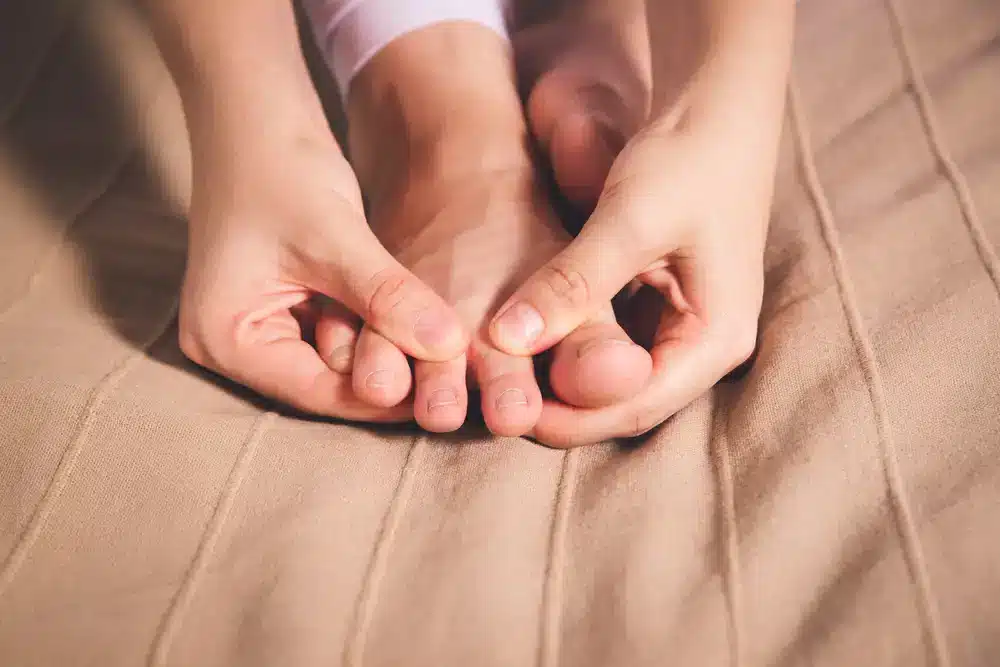 Osoba si prehmatáva oblasť okolo palca na nohe, čo môže byť spojené s liečbou dnových symptómov.