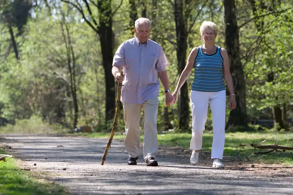 Starší pár sa prechádza v prírode, pravidelná chôdza môže pomôcť predchádzať hemoroidom bez potreby operácie.