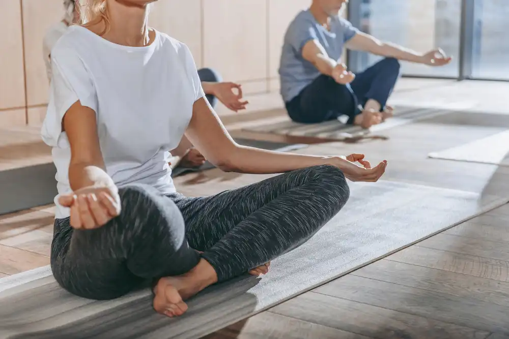 Ľudia sedia v meditačnej pozícii – meditácia a mindfulness pre zlepšenie duševnej rovnováhy.