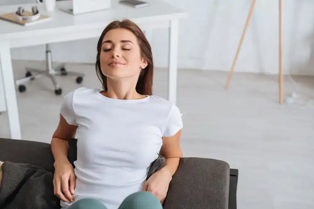 Mladá žena relaxuje na gauči so zatvorenými očami – dôležitosť mentálneho zdravia v biohackingu.