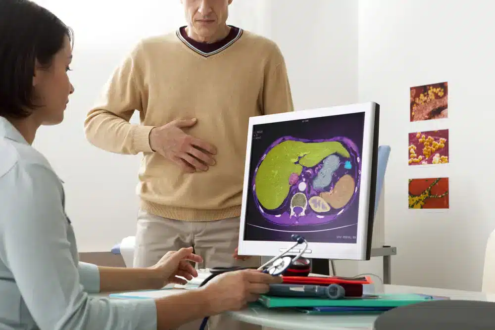 Lekárka ukazuje pacientovi CT snímku pečene s možnými metastázami.
